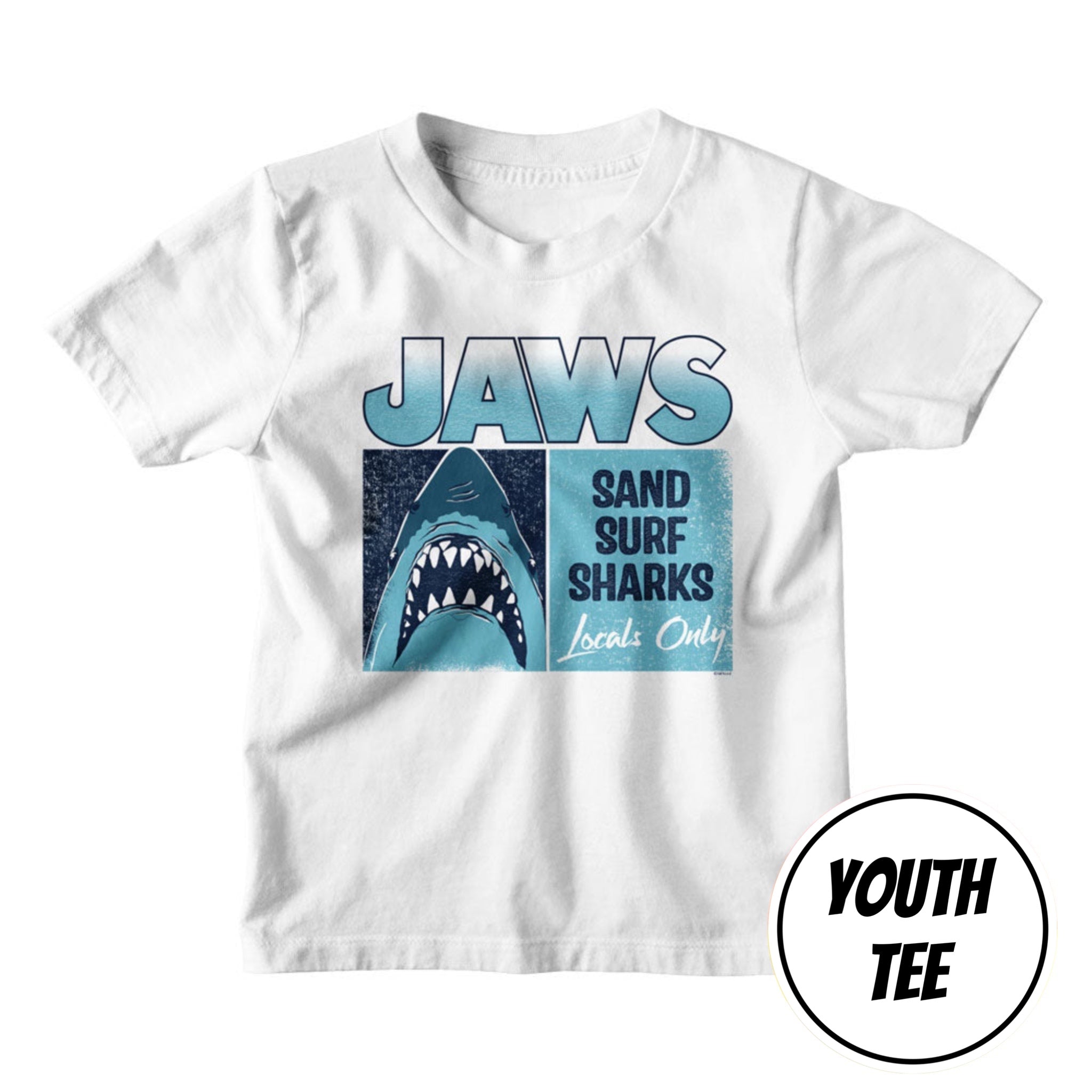 A white youth t-shirt featuring a 'Jaws' themed graphic print with a shark illustration and the text 'Sand Surf Sharks Locals Only'. A circular badge in the bottom right corner reads 'YOUTH TEE'.