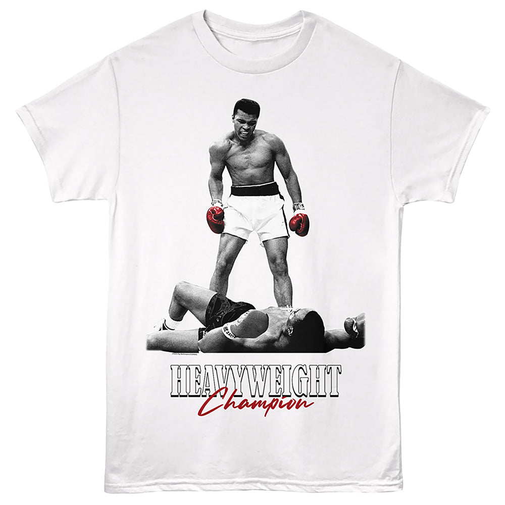 A white short-sleeve crewneck t-shirt featuring a graphic print of boxer Muhammad Ali standing over a defeated opponent, with the text 'HEAVYWEIGHT Champion' printed below in black and red.