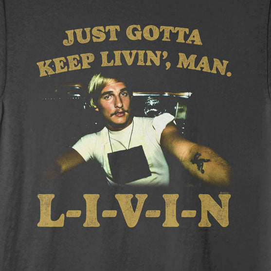 Black t-shirt with a graphic of a man and text 'Just Gotta Keep Livin', Man. L-I-V-I-N' on a white background.
