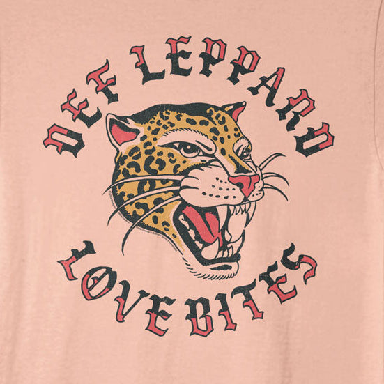 A peach-colored short-sleeve t-shirt featuring a graphic print of a roaring leopard with the text 'DEF LEPPARD' above and 'LOVE BITES' below in a stylized red and black font.