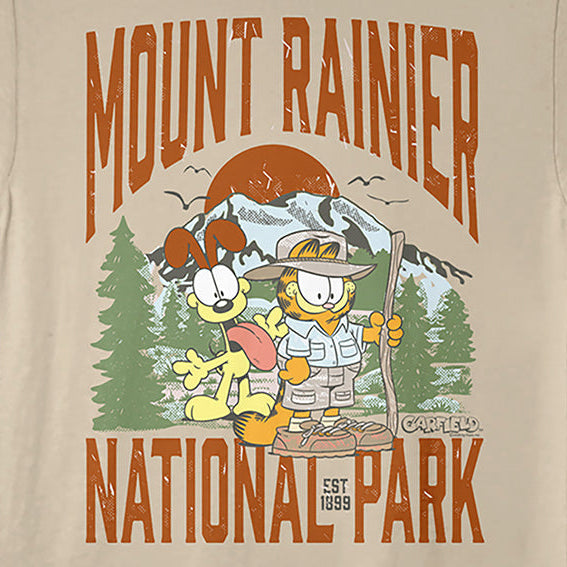A beige crewneck t-shirt featuring a colorful graphic print of Garfield and Catbus Charlie in front of a mountain, with 'MOUNT RAINIER NATIONAL PARK' printed in distressed orange text.