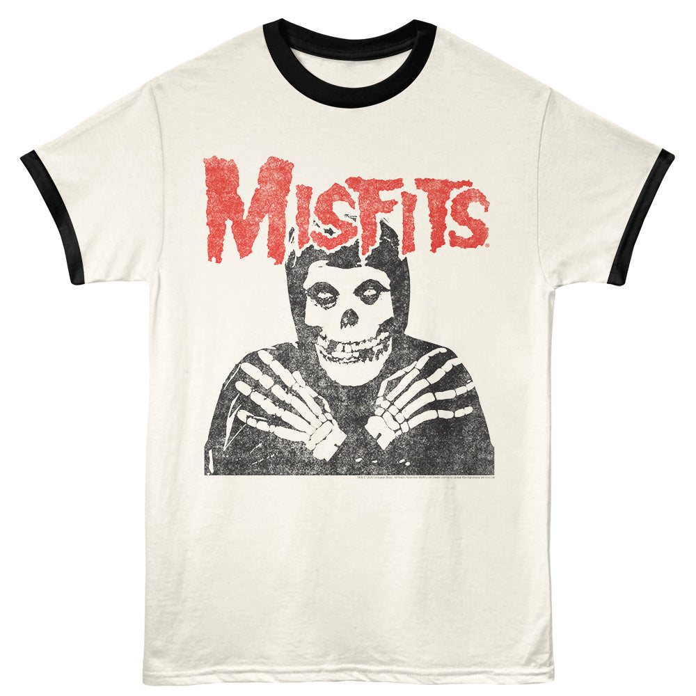 An off-white ringer t-shirt with black trim on the collar and sleeves, featuring a distressed red 'MISFITS' logo and a black-and-white graphic of a skeleton in a hood on the front.