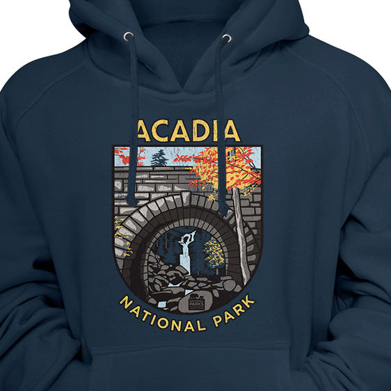 A navy blue pullover hoodie featuring a graphic print of Acadia National Park on the chest, displayed against a navy background.