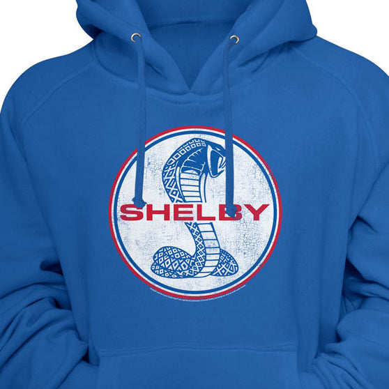 A royal blue pullover hoodie featuring a circular chest graphic with a coiled cobra snake and the word 'SHELBY' in red and blue.