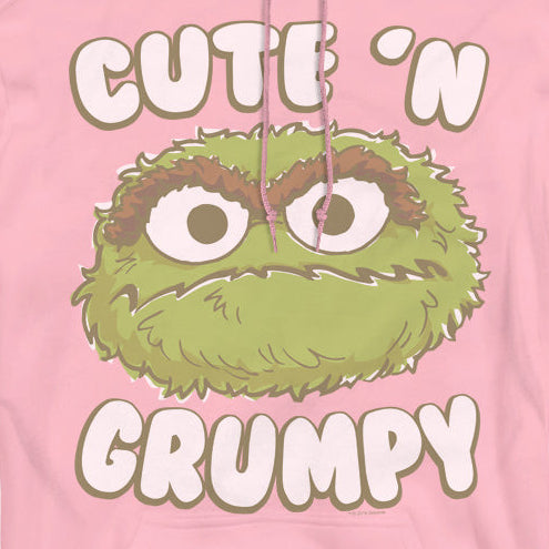 A pink pullover hoodie featuring a green cartoon character graphic with the text 'CUTE 'N GRUMPY' in white outlined letters.