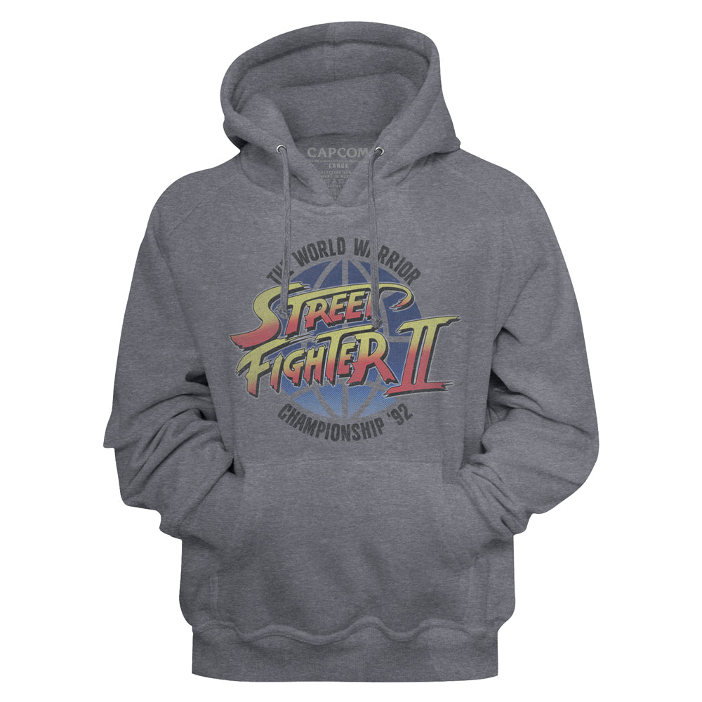 A heather gray pullover hoodie featuring the colorful 'Street Fighter II' World Warrior 'B' Championship '92' graphic on the chest, with a visible Capcom logo printed inside the collar.